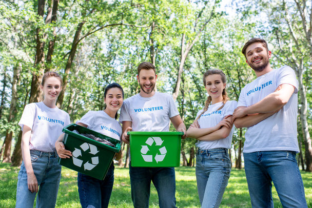 jóvenes voluntarios con cajas de reciclaje verdes después de limpiar el parque
  - Foto, Imagen