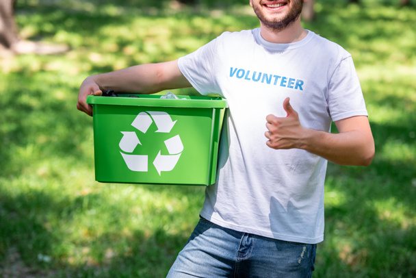 cropped view of man holding recycling box and showing thumb up - Foto, Bild