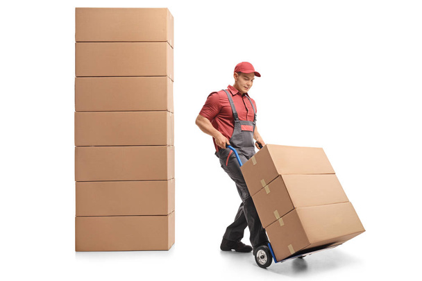 Mover with a hand truck next to a stack of boxes isolated on white background - Foto, afbeelding