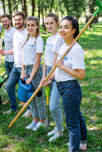 young smiling volunteers standing in park  - Photo, Image