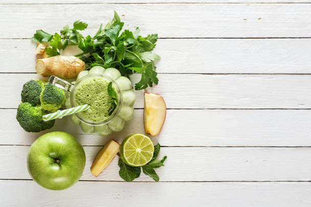 Batidos verdes frescos con perejil, jengibre, manzana, lima, pepino, brócoli y menta en un vaso sobre tablas blancas. El concepto de una dieta saludable. Copiar espacio
 - Foto, imagen