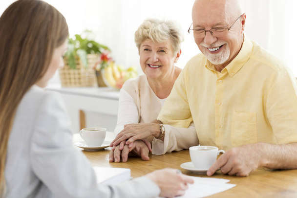 Happy senior man and his wife conversing with financial advisor about a loan - Foto, Imagen