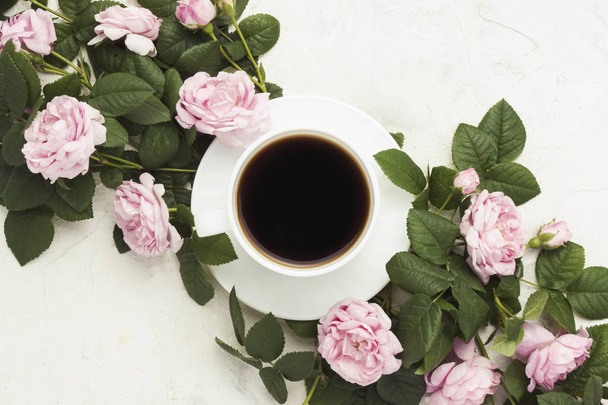 Bílý hrnek s černou kávu a růžové růže na světlém pozadí kamene. Plochá ležel, horní pohled. - Fotografie, Obrázek