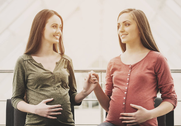 Two smiling pregnant women holding hands - 写真・画像