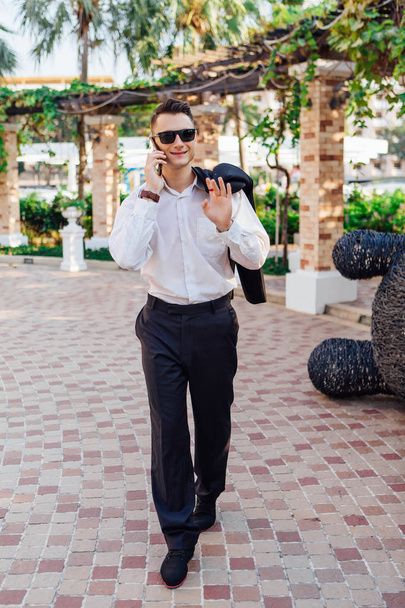 Young businessman talking on his phone outdoors in a tropical country - Fotoğraf, Görsel