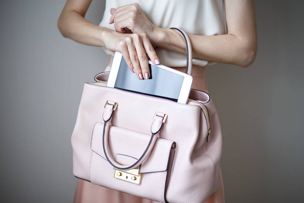 Digital electronic tablet on a woman's hands. Leather light pink handbag, summer elegant style - Foto, imagen