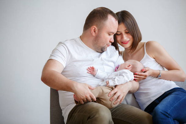 Portrait of happy married couple with newborn baby sitting on sofa - Fotografie, Obrázek