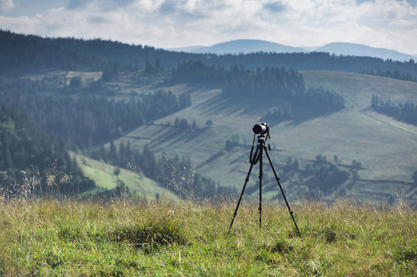 Camera and tripod set against the backdrop of mountain scenery - Photo, Image