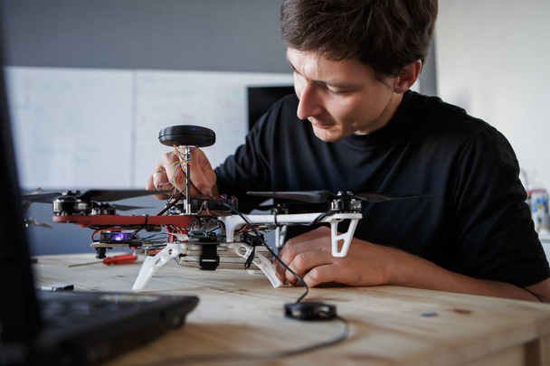 Photo of young man cleaning quadrocopter at table - Fotografie, Obrázek