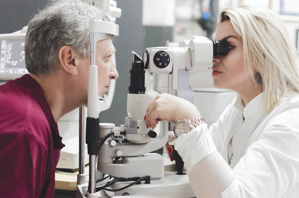 Refractometry. Keratometry. Refraction test. Optometry equipment. Man looking at refractometer eye test machine in ophthalmology, white empty screen - Foto, Bild