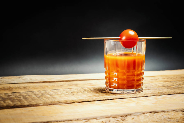 jugosa bebida María roja sangrienta con tomates en un palo sobre una mesa de madera
 - Foto, Imagen