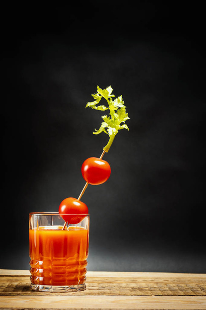 šťavnatá červená bloody mary nápoj s rajčaty na tyči na dřevěný stůl - Fotografie, Obrázek