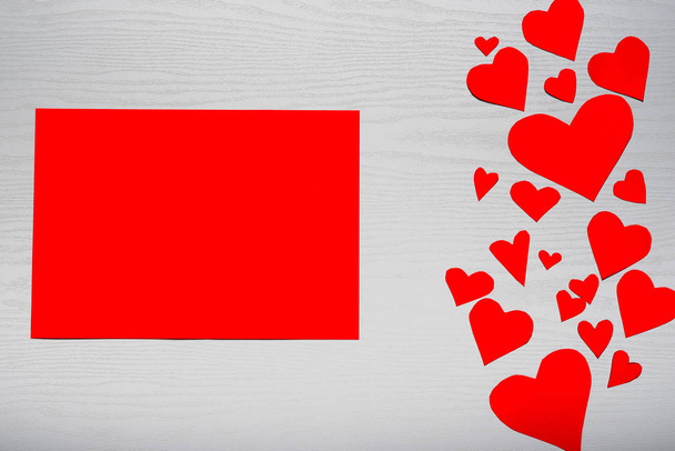 hölzerner weißer Hintergrund mit roten Herzen und rotem Blatt Papier. das Konzept des Valentinstages. - Foto, Bild