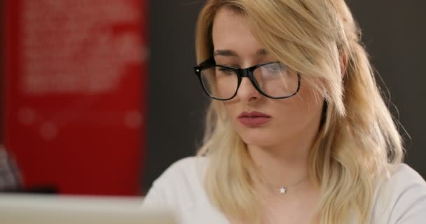 Close up portrait of gorgeous young businesslady in glasses at her workplace in the office, working at notebook. - Materiaali, video
