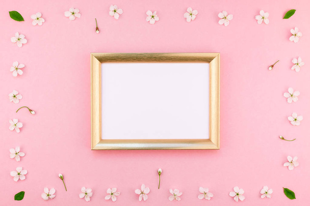 Creative flat lay concept top view of blank frame mock up and cherry tree flowers on pastel millennial pink background with copy space in minimal style, template for lettering, text or design - Foto, Bild