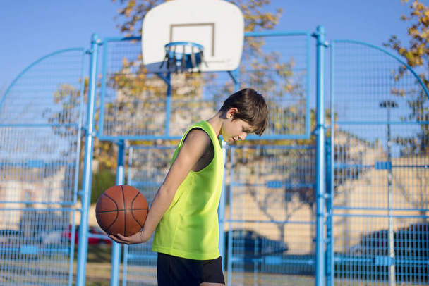 Mladí basketbalový hráč stojící na hřišti nosí žluté tílko - Fotografie, Obrázek