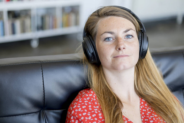 A head and shoulder shot of a woman looking into the camera with headphones - Foto, Imagen