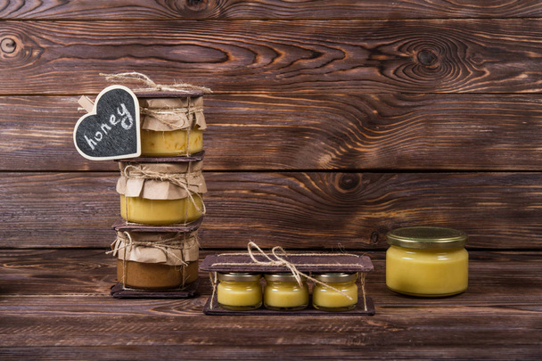 Honey in a glass jar on a dark wooden background. Bee Honey - Zdjęcie, obraz