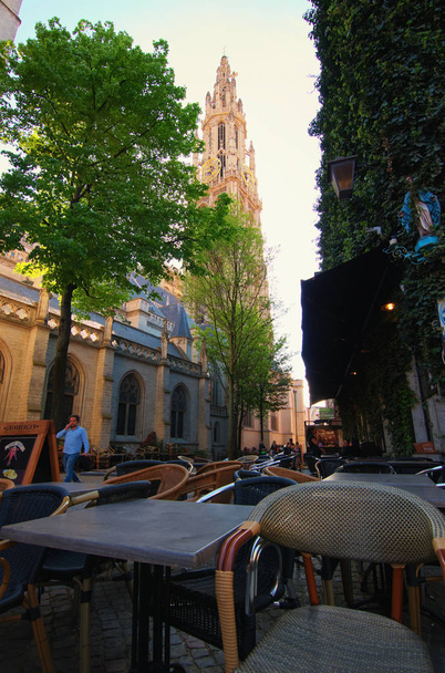 Antwerpen, Belgia-toukokuu 02, 2018: Kodikas kahvila rauhallisella kadulla, josta on viehättävä näköala Neitsyt Marian katedraalin torniin (hollantilainen: Onze-Lieve-Vrouwekathedraal
). - Valokuva, kuva