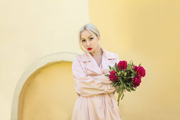 elegante blonde Frau mit Pfingstrosenblüten im Freien. Weibliches Model wartet - Foto, Bild
