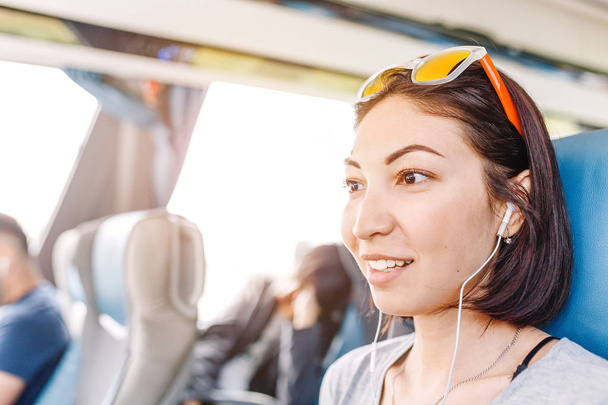 Müzik veya bir tren veya otobüs seyahat ederken dil öğrenme mutlu karışık ırk kadın yolcu - Fotoğraf, Görsel