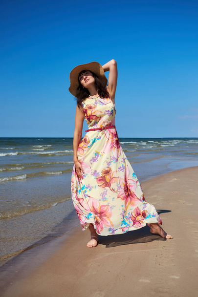 Relaxed girl with a hat is walking on the beach. Baltic Sea Coast, Latvia. - 写真・画像