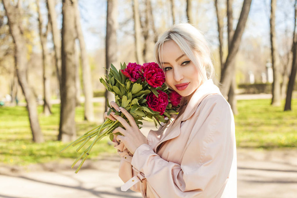 Cute young woman with flowers outdoors. Female model with peony portrait - Photo, Image