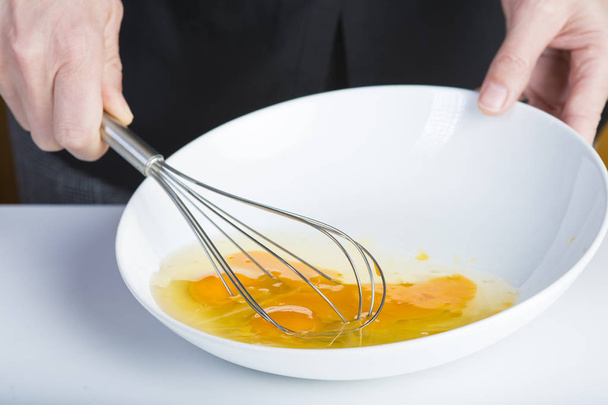 Chef batiendo huevos de pollo en un tazón conuna batidora manual
 - Foto, Imagen