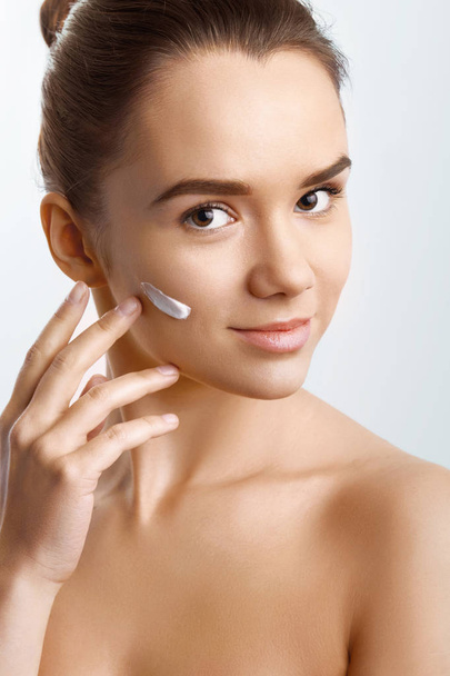 Beauty Skin Care. Beautiful Happy Woman Applying Cosmetic Cream On Clean Face. Closeup Portrait Of Healthy Smiling Female Model With Natural Makeup, Fresh Soft Pure Skin Applying Moisturizing Lotion - Fotó, kép