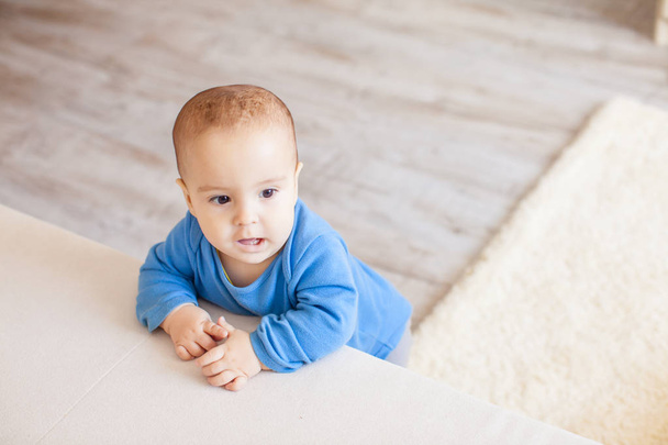 First steps near the sofa. Cute toddler boy try to stand and walk - Foto, Imagem