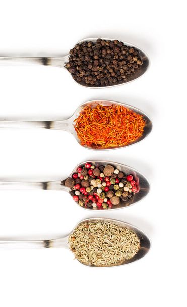 Different spices in iron spoons isolated on white background. View from the top of dried rosemary, saffron, pepper.  - Photo, Image