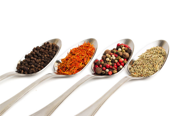 Different spices in iron spoons isolated on white background. Dried rosemary, saffron, pepper.  - Фото, изображение