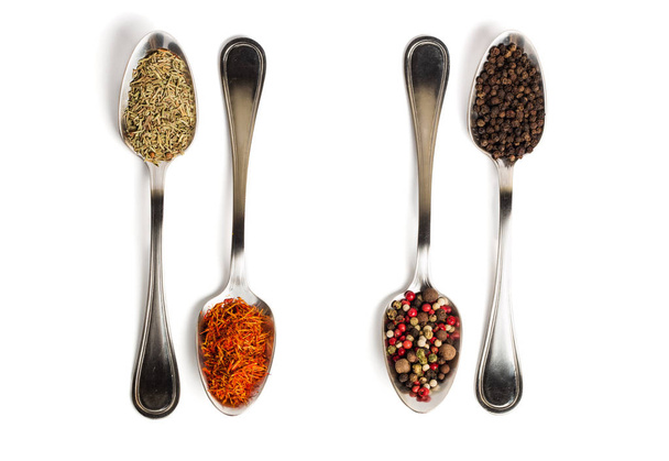 Different spices in iron spoons isolated on white background. View from the top of dried rosemary, saffron, pepper.  - 写真・画像