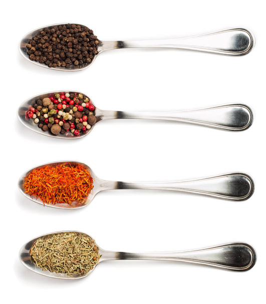 Different spices in iron spoons isolated on white background. View from the top of dried rosemary, saffron, pepper.  - Foto, immagini