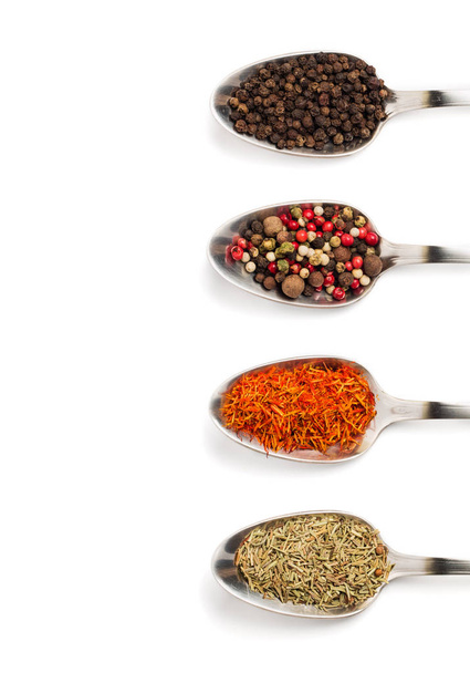 Different spices in iron spoons isolated on white background. View from the top of dried rosemary, saffron, pepper.  - 写真・画像