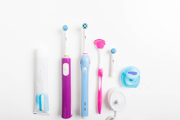 Brosses à dents électriques rechargeables, nettoyant pour la langue et autres accessoires dentaires sur fond clair
 - Photo, image