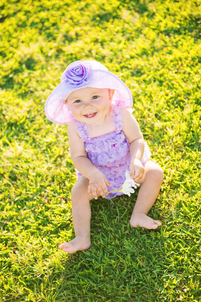 Portrait of a happy girl on vacation. A girl in purple is sitting on the lawn - Photo, image