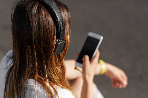 Girl listening music sitting on sidewalk - Foto, immagini