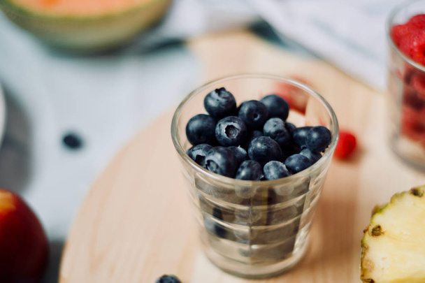 tasty healthy eating vegetarian vegan detox breakfast with fresh seasonal fruits and berries served on chopping board over pastel blue background - Fotoğraf, Görsel