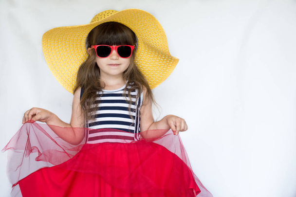 Całkiem mała dziewczynka w pasiasty strój i kapelusz gotowy na lato, wakacje, Podróże koncepcja. Dziewczynka w okularach kapelusz i słońce - Zdjęcie, obraz