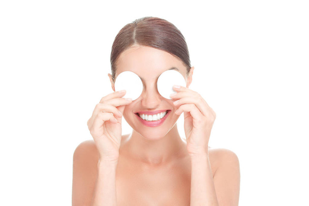 Woman happy covering eyes with cotton pads smiling toothy isolated on white background wall. Face care, natural beauty, eye cotton pads mask. Mixed race african american caucasian brazilian model - Φωτογραφία, εικόνα