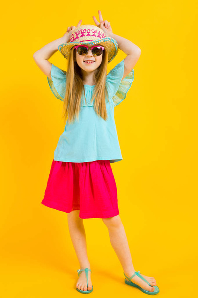Sarı bir arka plan üzerinde kırmızı saçlı kız. Parlak yaz giysileri sevimli bir kız kendini boynuzları yaptı. - Fotoğraf, Görsel