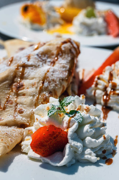 pancake with apple filling decorated with whipped cream, strawberries and oranges - Photo, Image