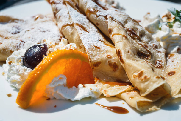 pancake with apple filling decorated with whipped cream, oranges and cherry - Photo, Image