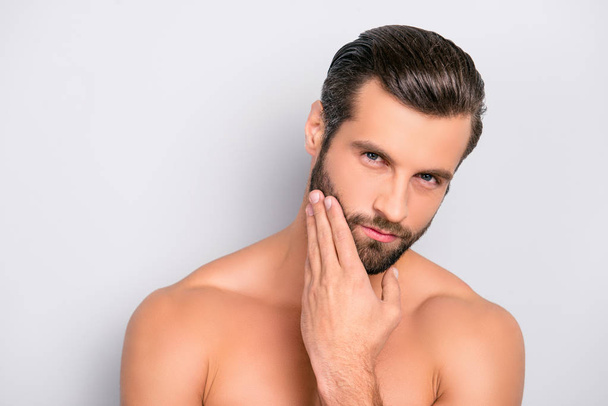 Attractive, brutal, modern, manly, virile, confident, dreamy, naked man touching his perfect, ideal face skin, holding hand on beard, cheek, looking at camera, isolated over gray background - Photo, image