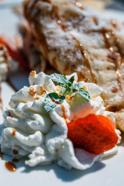 pancake with apple filling decorated with whipped cream, strawberries and oranges - Photo, Image
