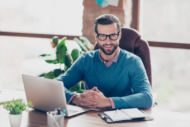Stunning, smiling, harsh, virile, IT-manager in glasses, pullover, shirt, sitting on leather chair at desktop in workplace, looking at camera - Fotó, kép