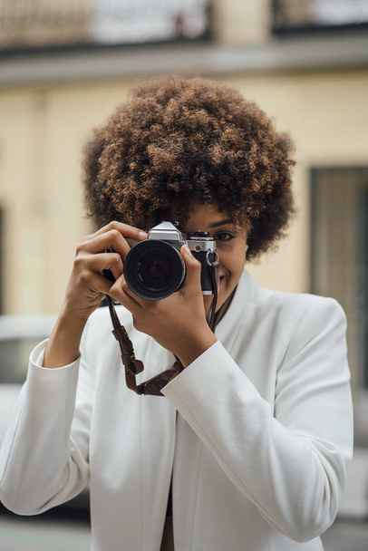 Female photographer visiting Madrid with an old analog camera. Afro race young woman, 21 years old. - Photo, Image
