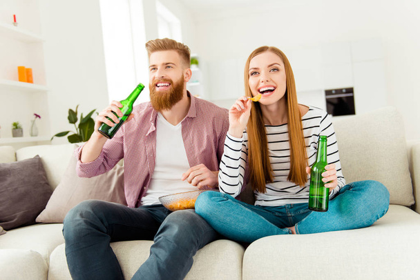 Weekend holiday vacation joy enjoy leisure fun date concept. Excited cheerful joyful delightful attractive rejoicing students eating junk food drinking alcohol beer sitting on divan watching sport - Zdjęcie, obraz