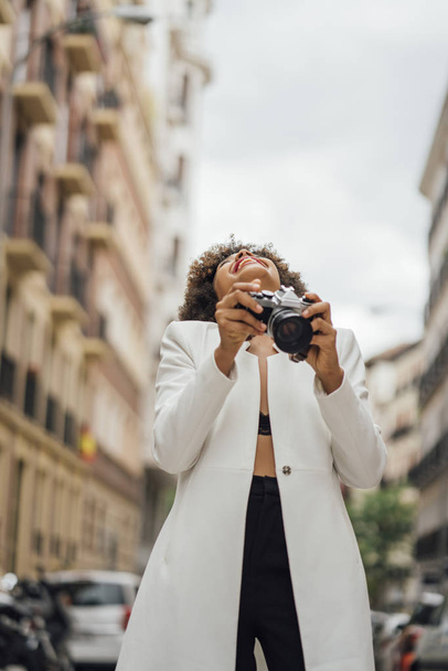 Fotógrafa visitando Madrid con una vieja cámara analógica. Afro race mujer joven, 21 años
. - Foto, Imagen